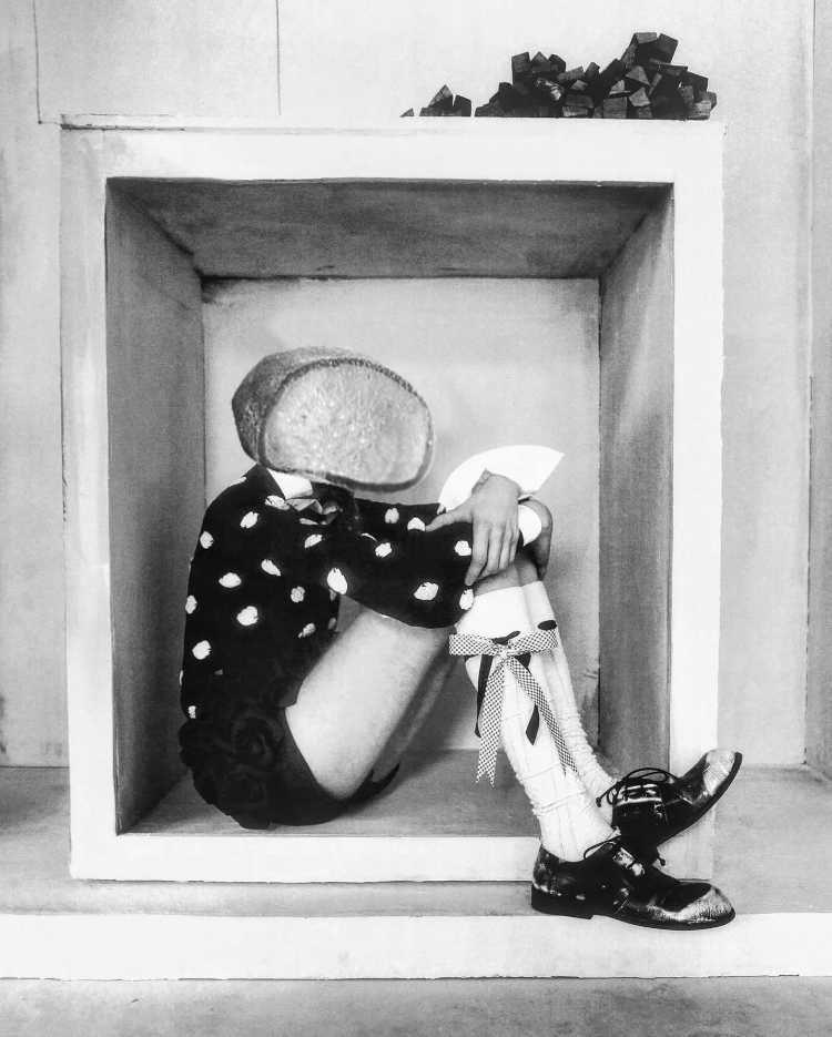 model sitting in box wearing polka dot top and black shorts